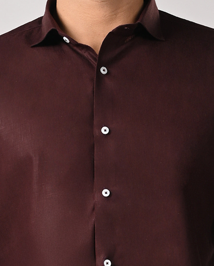 Close-up of a maroon shirt with white buttons on a plain background