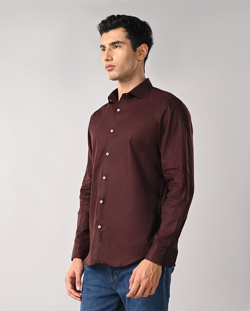 Man wearing a maroon shirt and blue jeans on a gray background