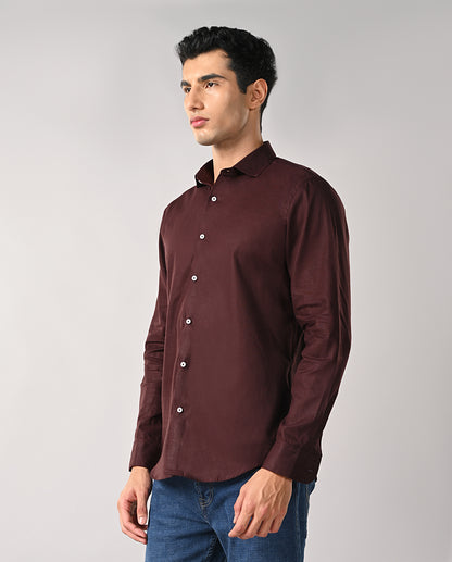 Man wearing a maroon shirt and blue jeans on a gray background