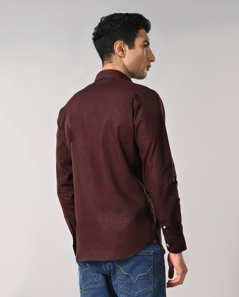 Man wearing a maroon shirt and blue jeans on a gray background